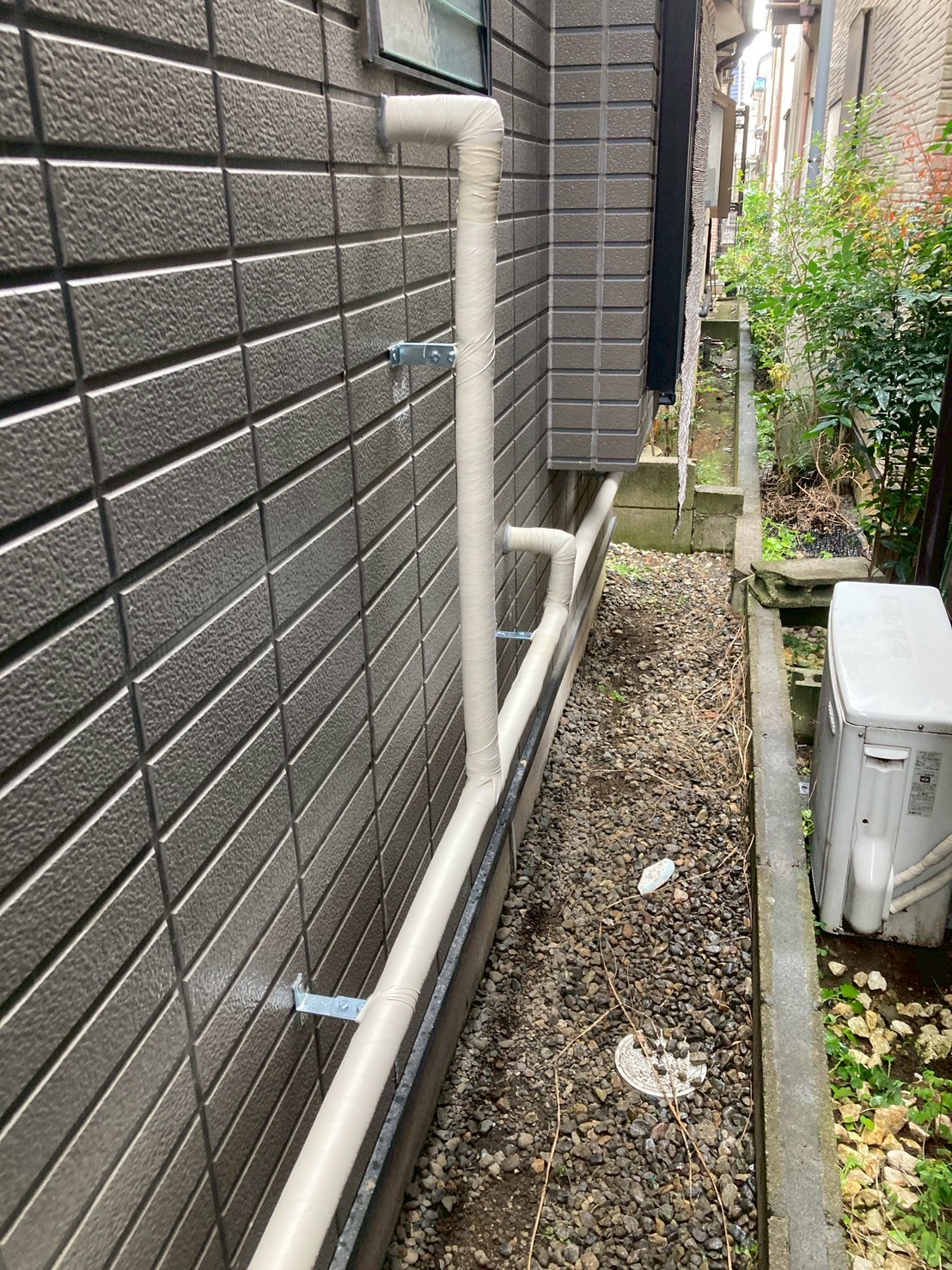 外壁面に這わせた新規保温付き配管の全体像。ブラケットで整然と固定されている