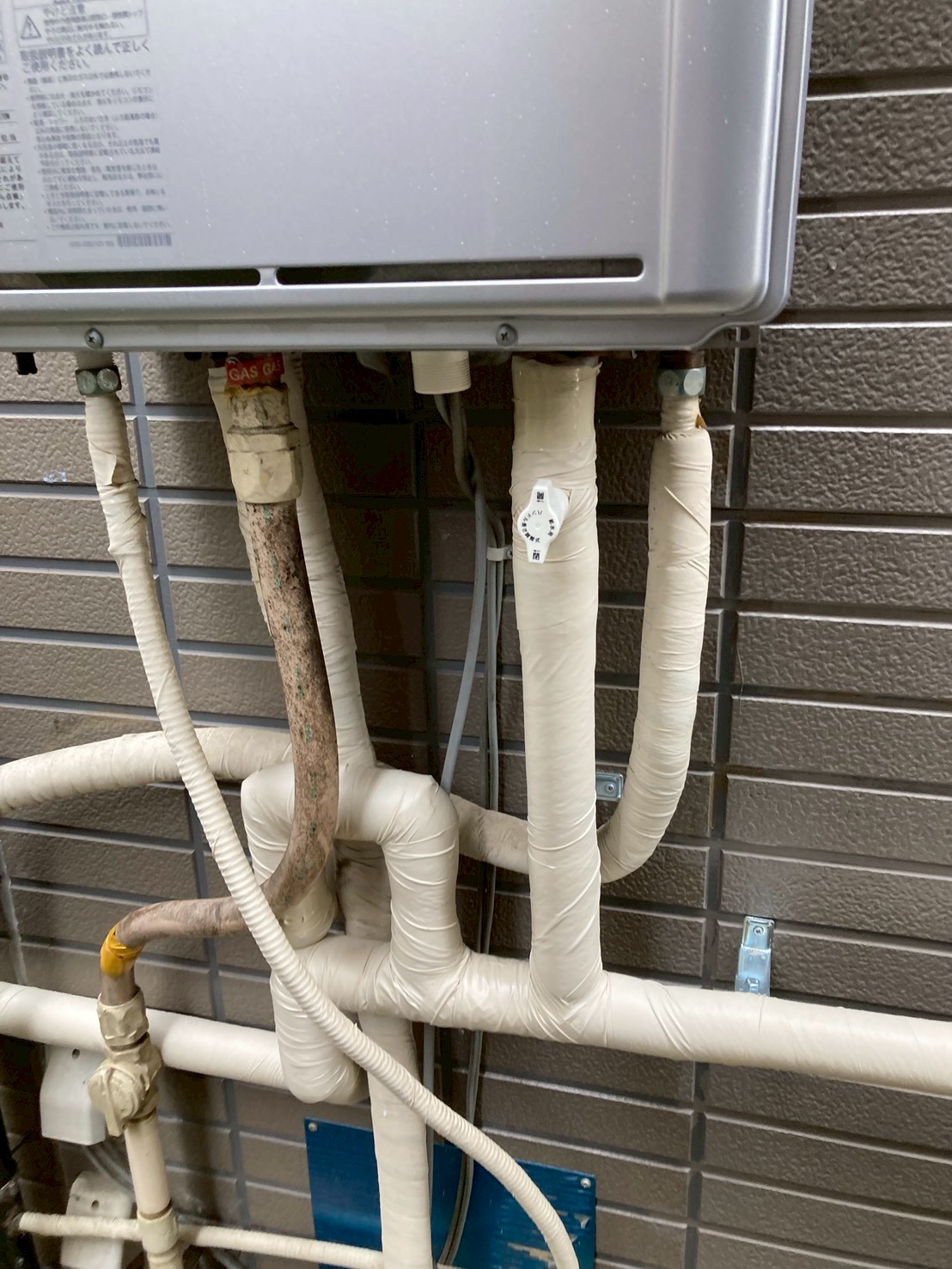給湯器下部の複雑に入り組んだ配管群。GASラベルのガス管と水道管が混在している