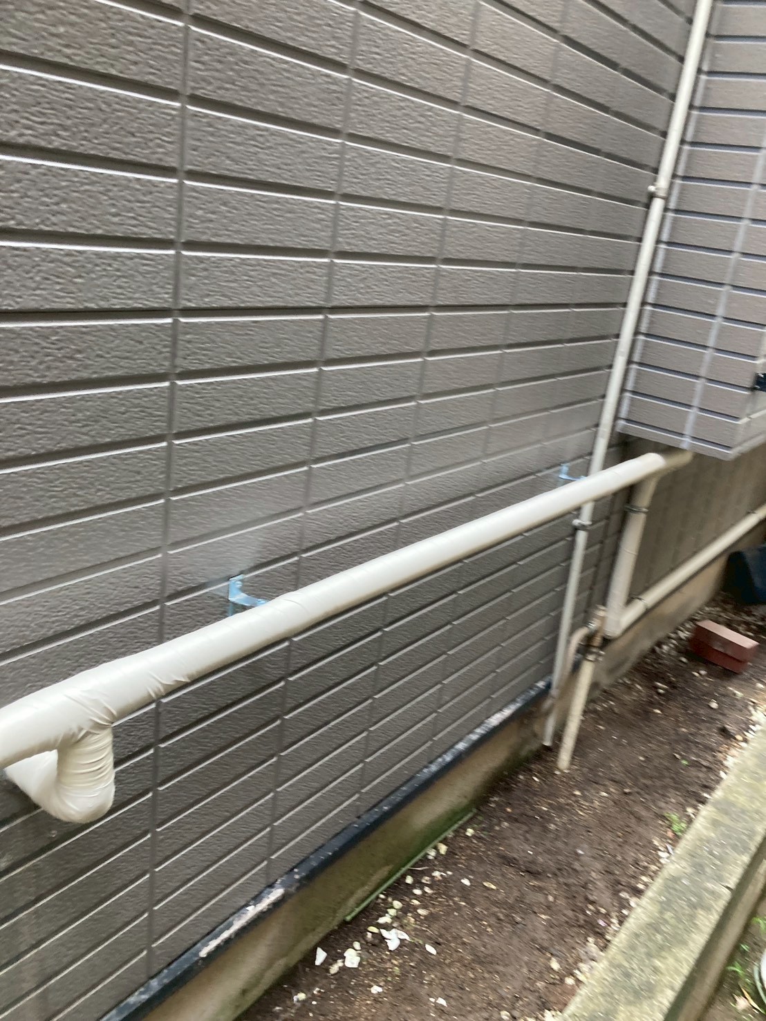 別面外壁に敷設された新規保温配管の全景。壁面に整然とブラケット固定されている