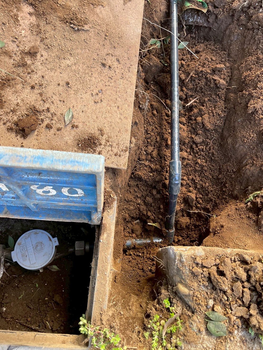 水道メーター周辺を掘削した様子。地中に埋設された既存給水管と新規HIVP管が確認できる