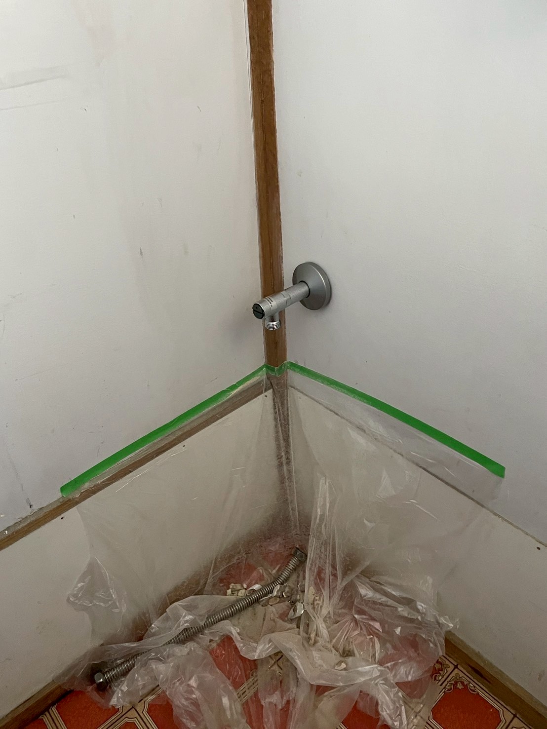 トイレ内の新規給水管壁出し口にアングル止水栓を設置した状態。床面の養生も確認できる