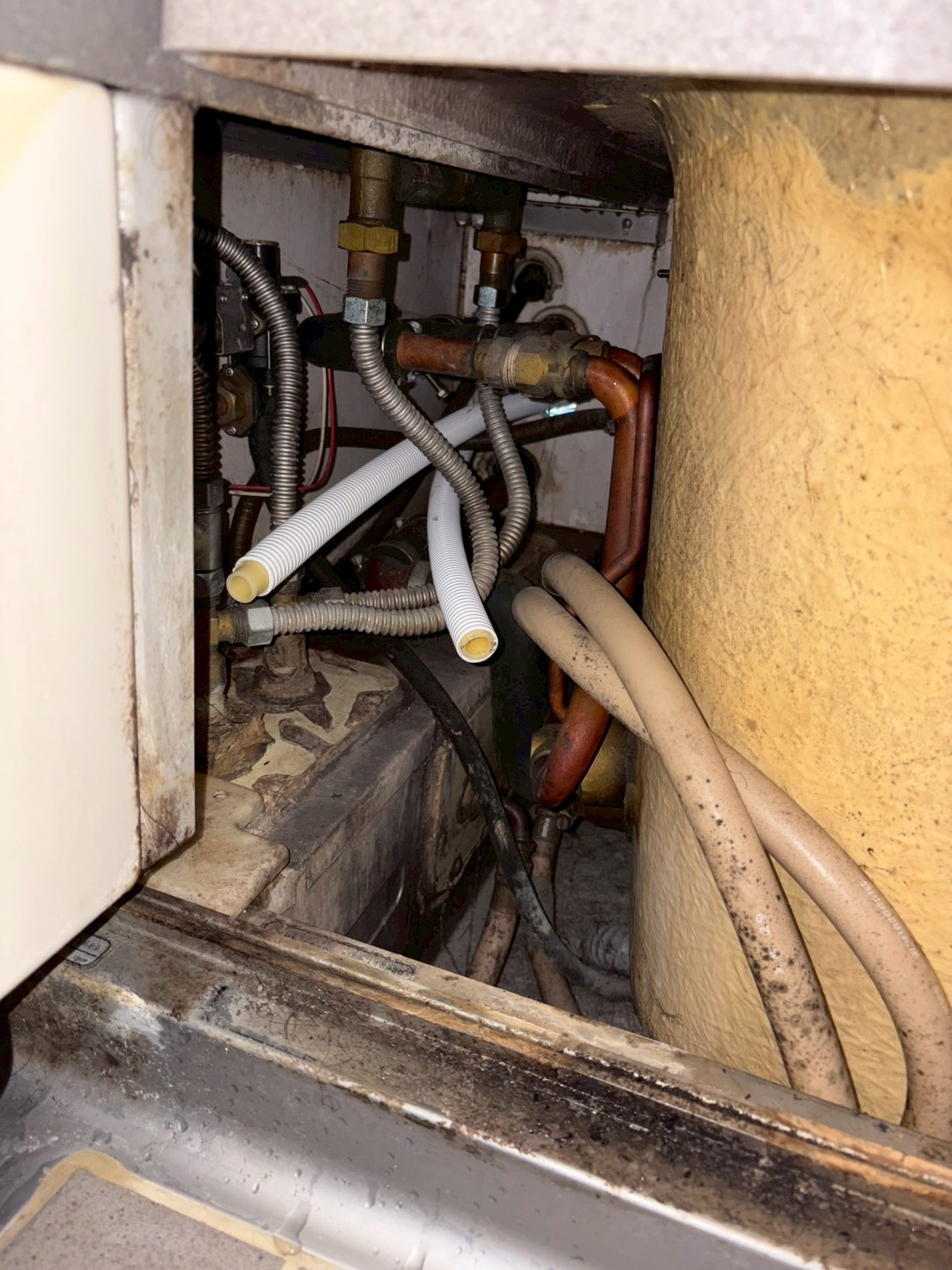 浴室床下点検口内の既存給湯配管。銅管・フレキ管・コルゲート管が複雑に混在し著しく老朽化している