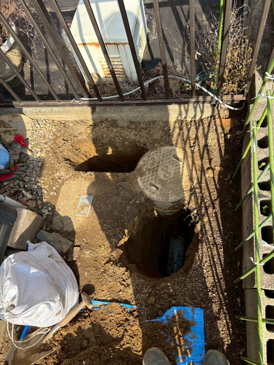 マンホール周辺の地面を掘削した状態。マンホール蓋が露出し排水桝の周囲の土が大きく掘り起こされている