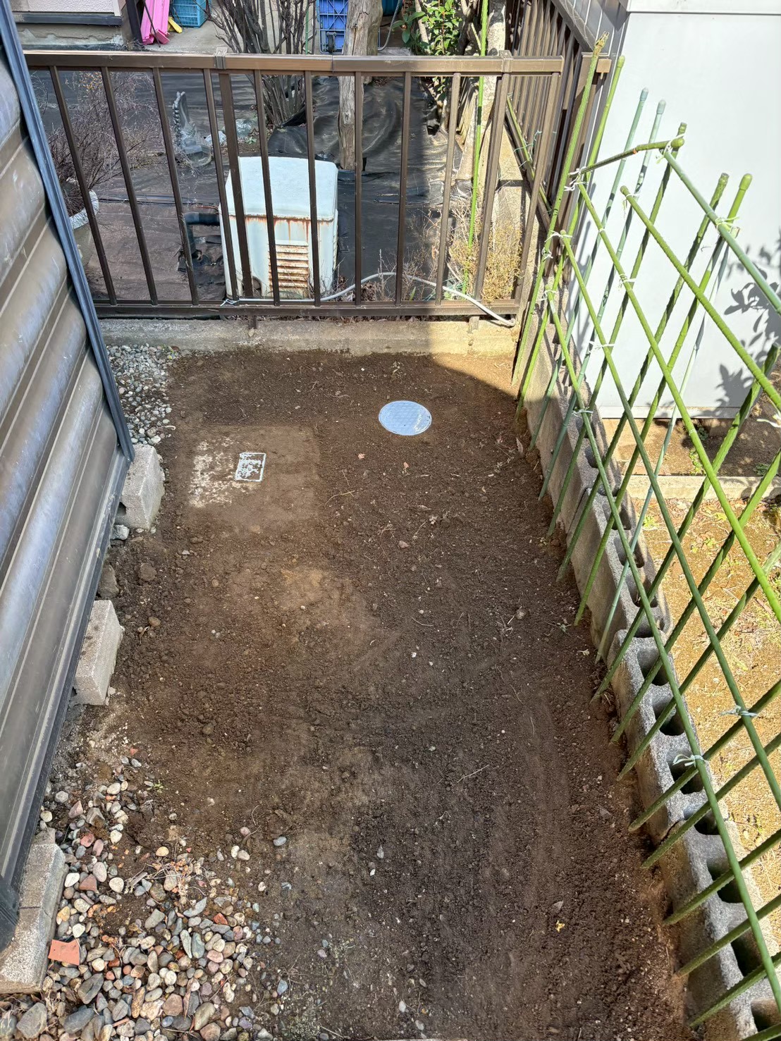 作業完了後の敷地全景。掘削した土が埋め戻されて整地され、新しいマンホール蓋が設置された状態