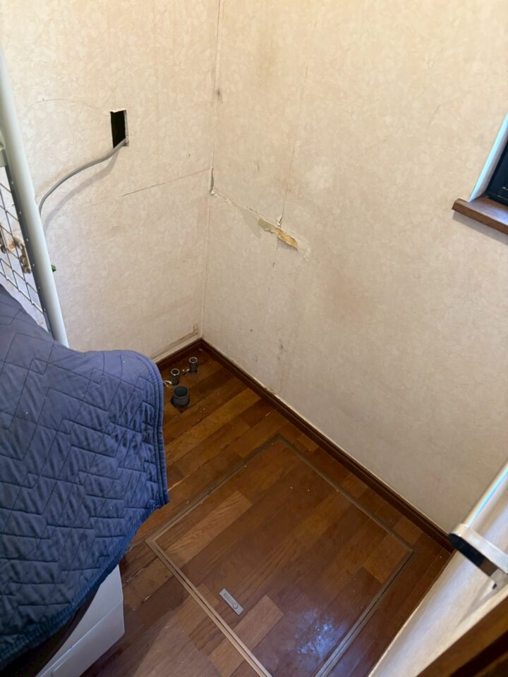 旧洗面台撤去後の壁面（水漏れによる染みと壁紙の剥がれ）