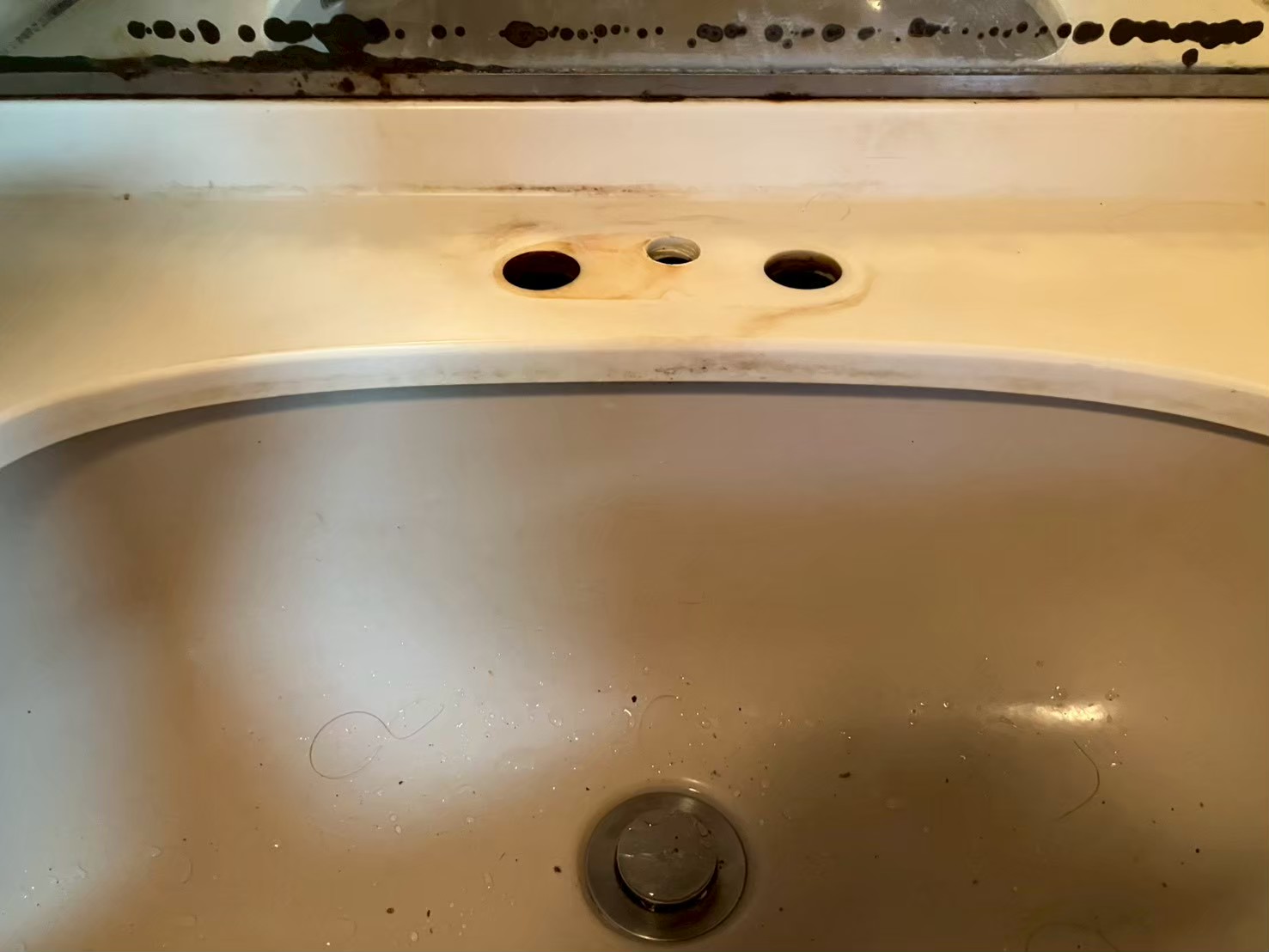 旧水栓を取り外した後の洗面台天板。3ホールの取付穴が露出し、穴周辺に水漏れによる変色が残っている