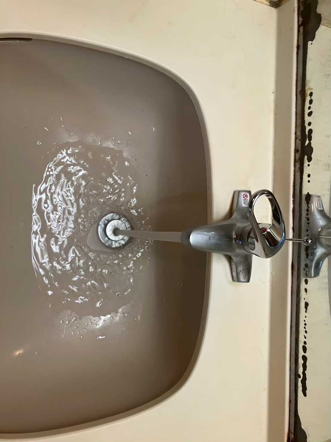 新しいシングルレバー混合水栓を取り付け後、通水確認中。水が勢いよく流れている