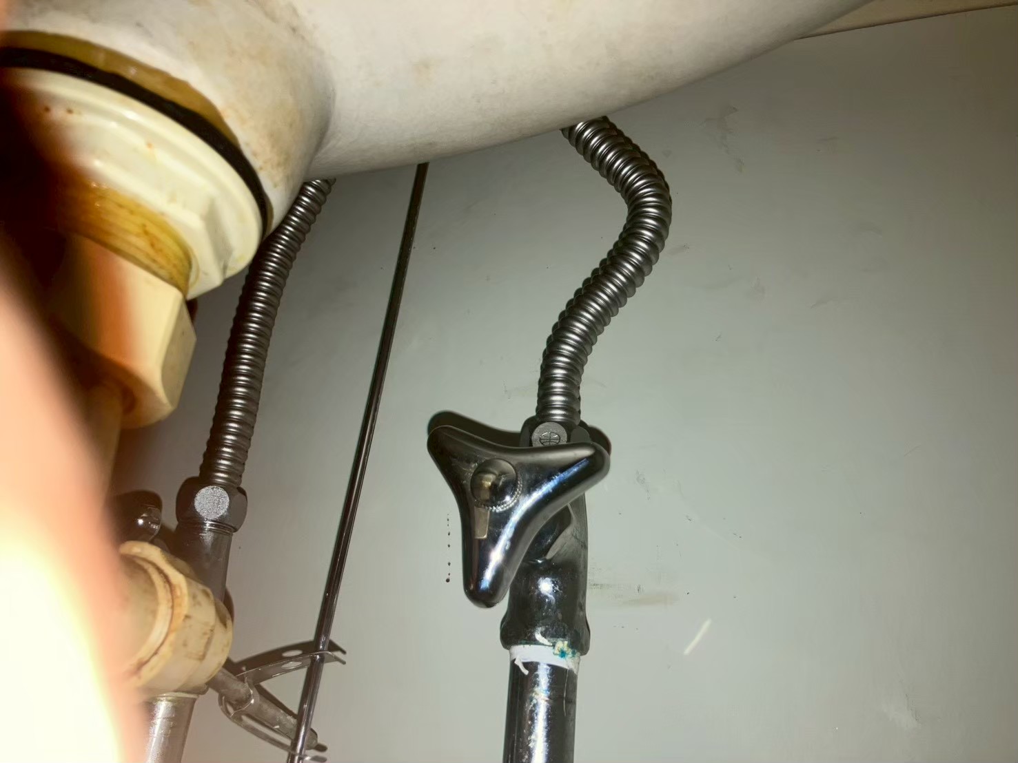 シンク下の配管。新水栓のフレキ管が止水栓を介して既存の給水管・給湯管に接続されている