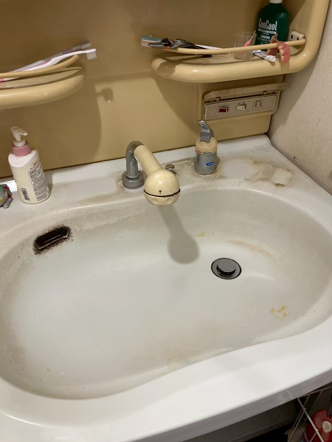 施工前の洗面台上面。旧型2ハンドル水栓が腐食・変色し台座周辺に白いスケールが大量付着している