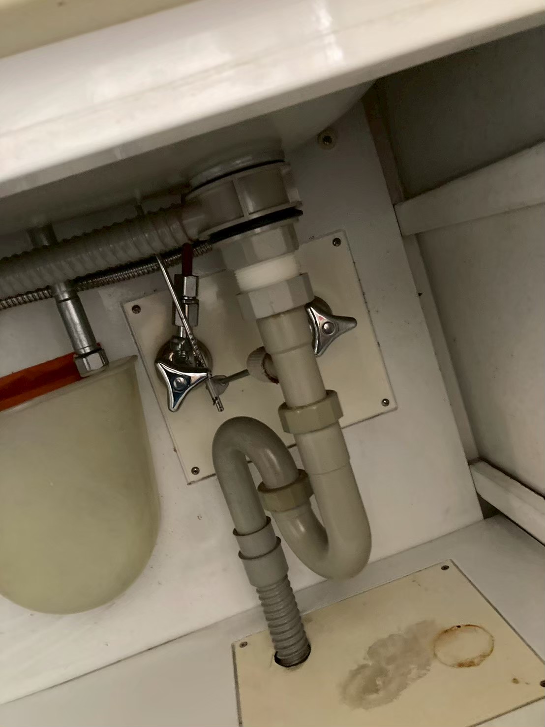 施工前のキャビネット内部。底面に茶色い水漏れ跡のシミが確認できる