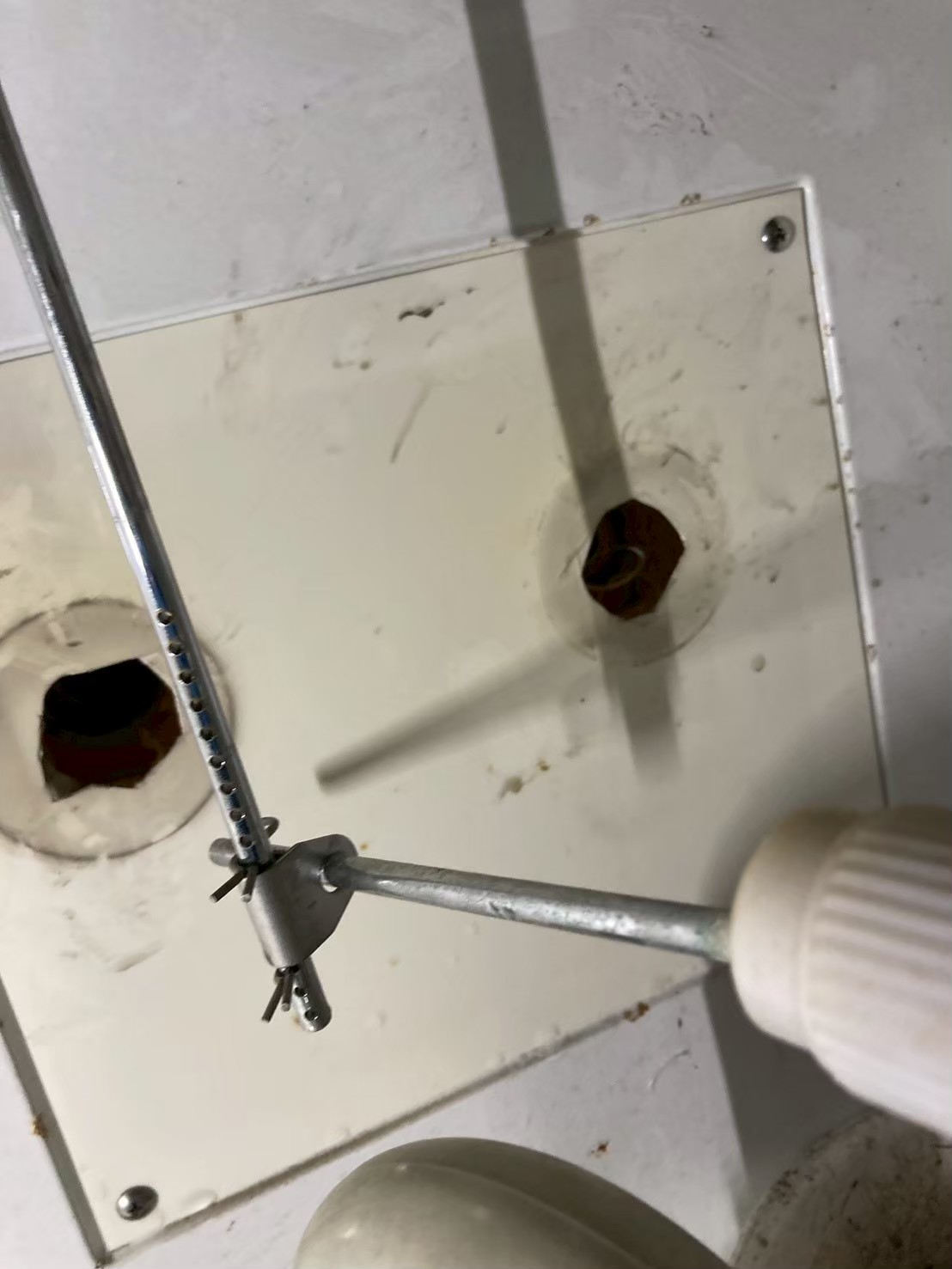 旧水栓取り外し後の壁面タイル。給水口の銅管が赤茶色に腐食しており電動ドライバーで作業中