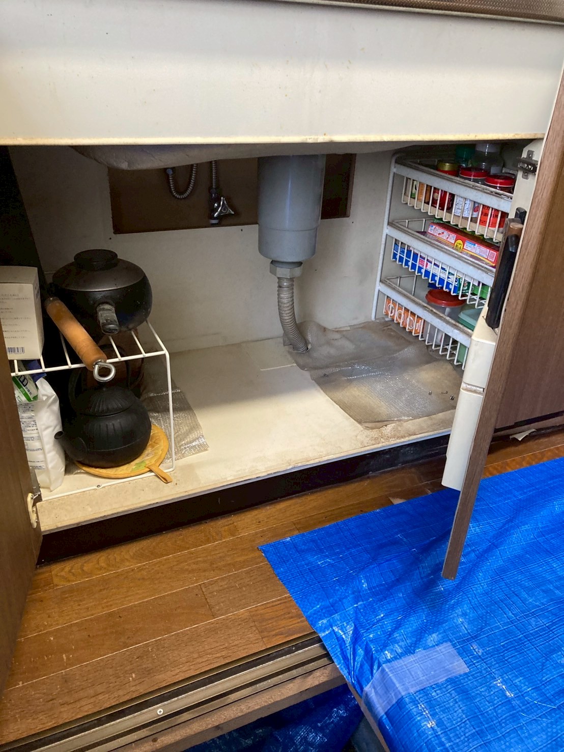 シンク下キャビネット内部。排水管まわりと給水管接続部を確認している