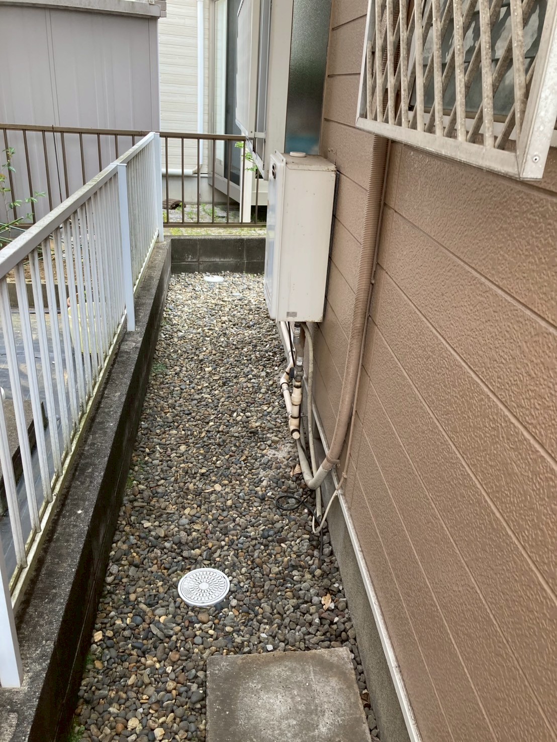 屋外に設置された老朽化した給湯器。本体下部の配管接続部に劣化の痕跡あり