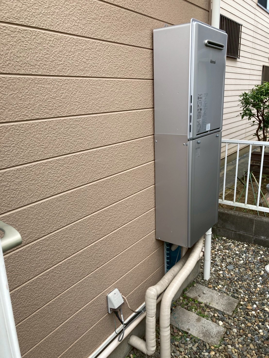 新品のRinnai製給湯器を外壁に設置した状態。下部に新規保温配管が接続されている
