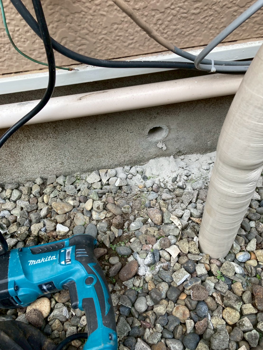 基礎部分に新規配管を通すための穴あけ作業中。マキタの電動ドリルを使用