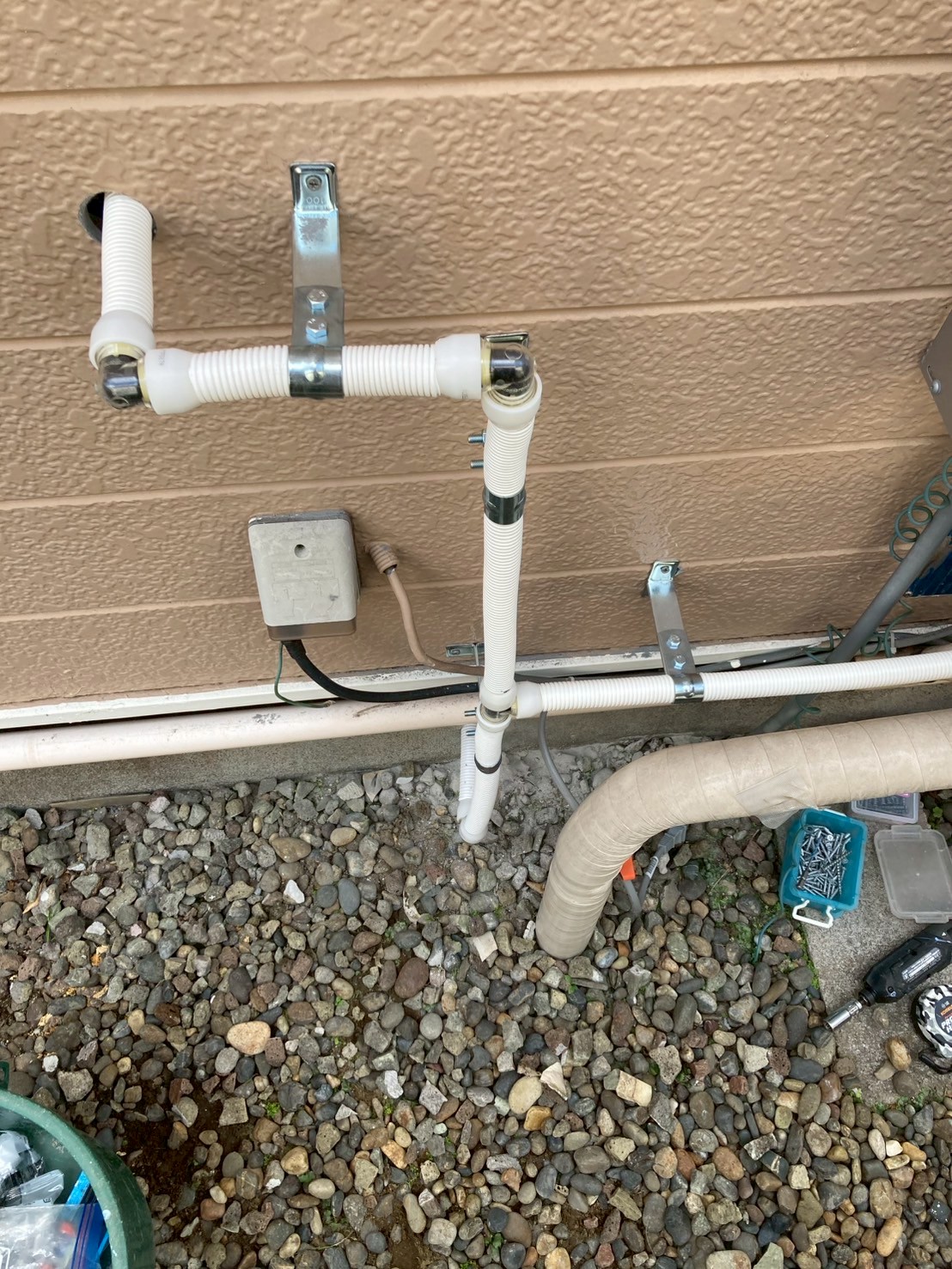 外壁面に整然と固定された新規フレキ配管の全体像。給水・給湯の2系統がブラケット固定されている