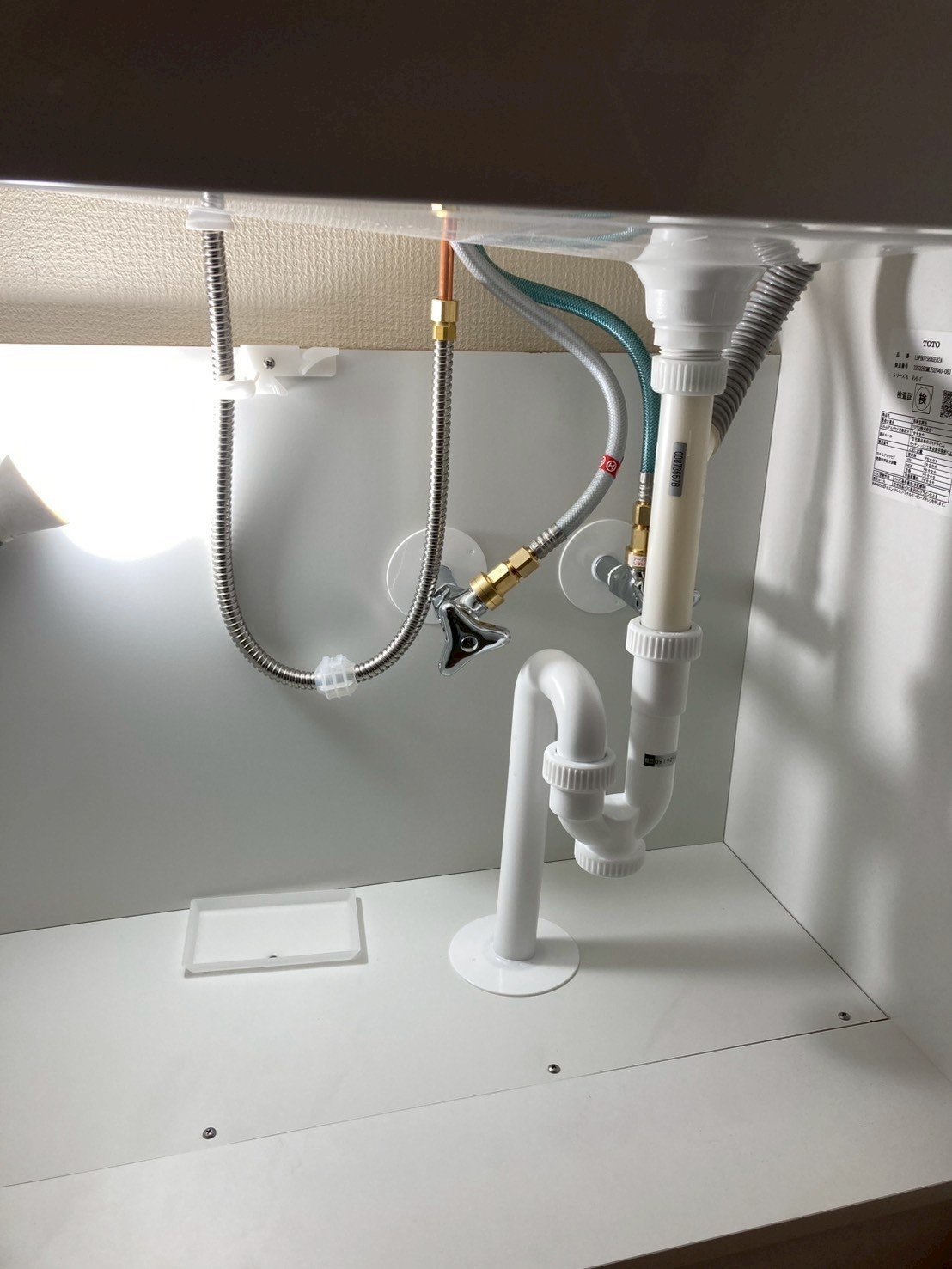 新品TOTO製洗面化粧台のキャビネット内部。フレキ管と排水トラップが正しく接続されている