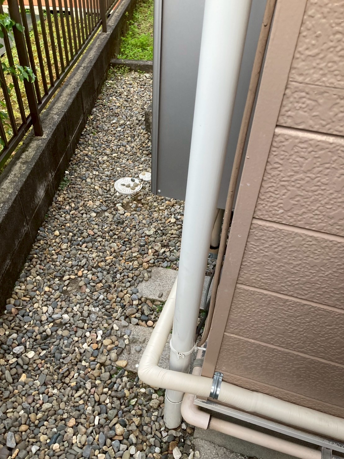 建物角部の新規配管立ち上がり部。2系統の配管がブラケット固定されて整然と壁面を這っている