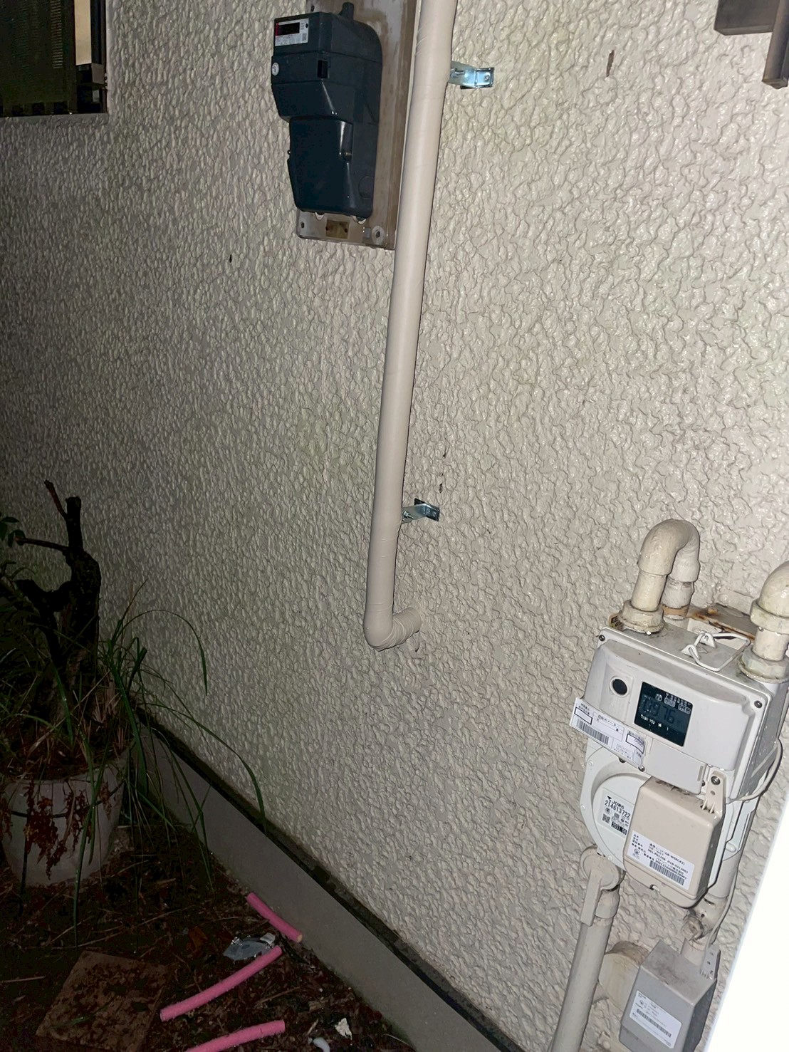 保温材で被覆された新規配管が外壁にブラケット固定された完成状態全景