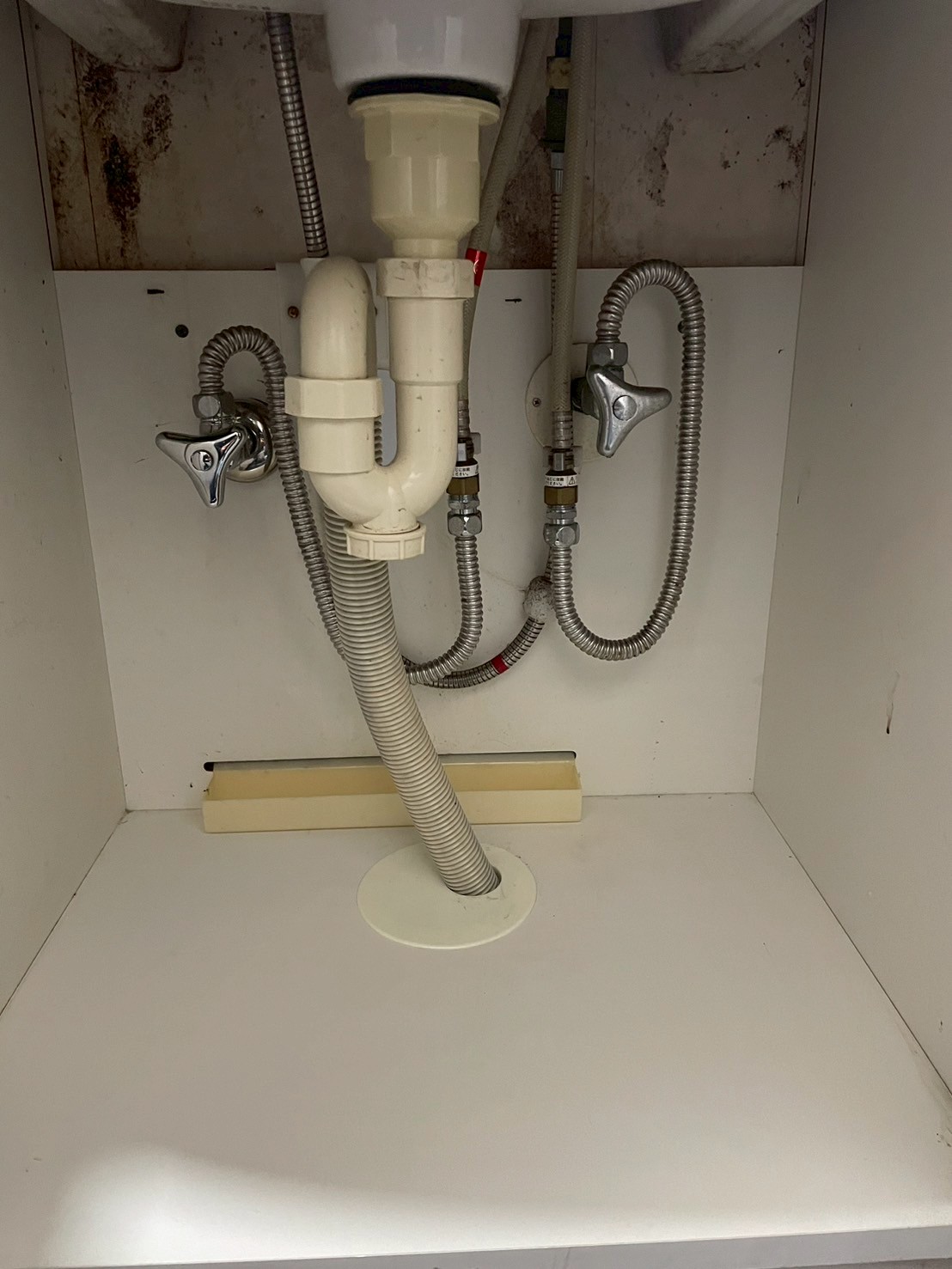 洗面台下の完成状態。新しいステンレスフレキ管で給水・給湯の止水栓が整備されている