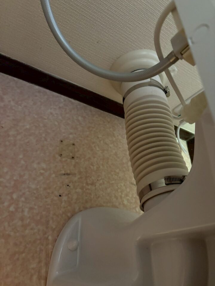 便器底部と排水管の接続部。蛇腹ホースをステンレスバンドで固定