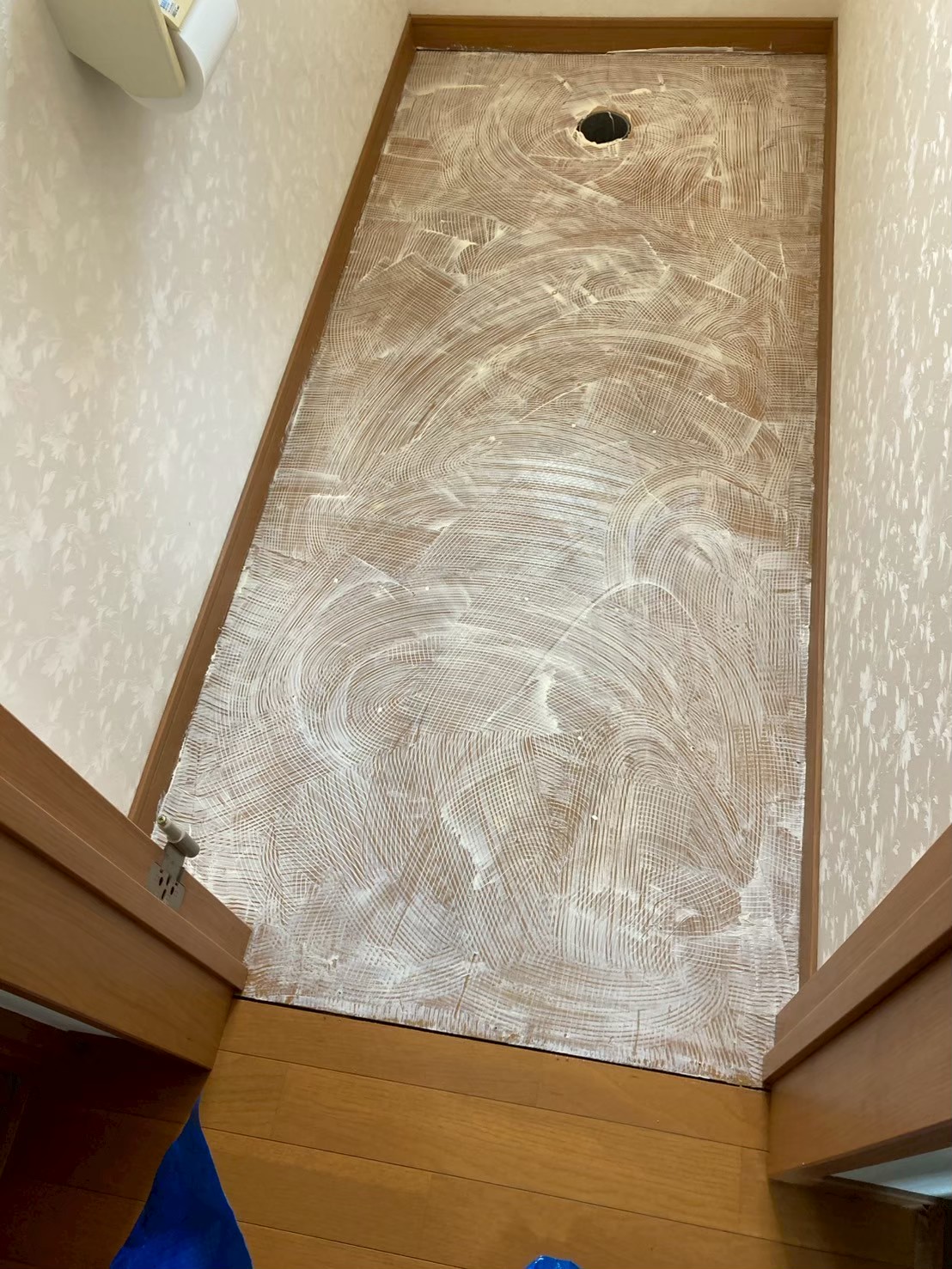 既存クッションフロアを剥がした状態。床材の裏面のメッシュ地が見えており、長期水漏れによる劣化・湿気ダメージが確認できる