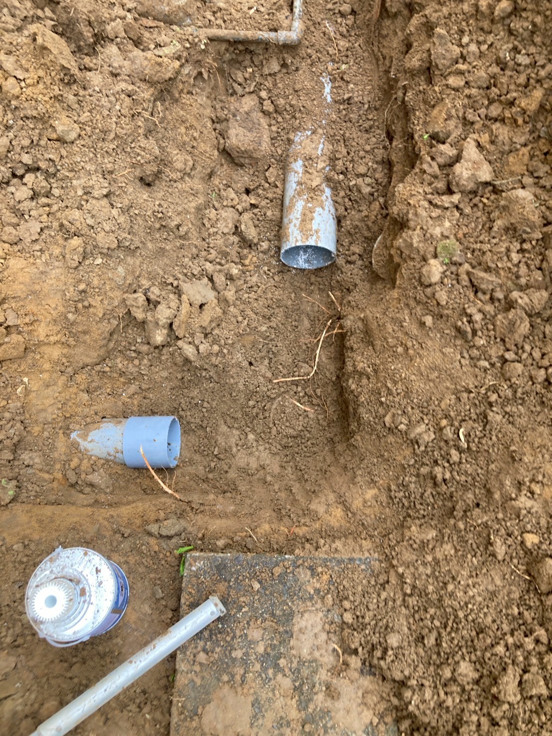 撤去した古い鋳鉄製排水管の断片が地面に置かれている。管内に樹木の根が侵入した痕跡がある