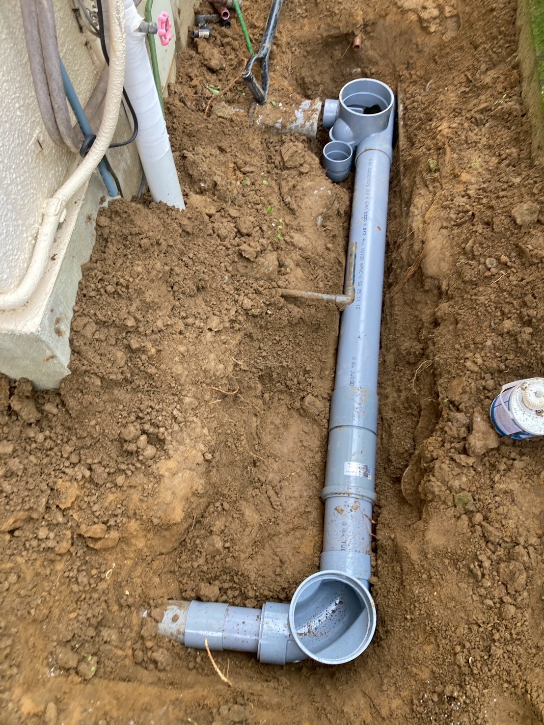 掘削した溝に新しい塩ビ製排水管を敷設している施工中の様子。Y字継手や合流管が接続されている