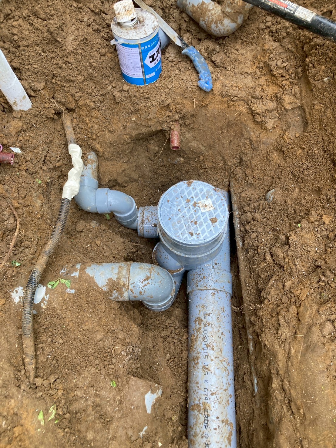 新設した塩ビ排水管の接続部に掃除口（点検口）が設置された状態。JIS K 674認定の塩ビ管を使用