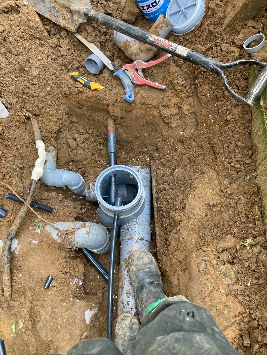 掘削した溝に新設の塩ビ排水管と新しい会所枡が設置された状態。エスロン接着剤を使用して配管を接続している