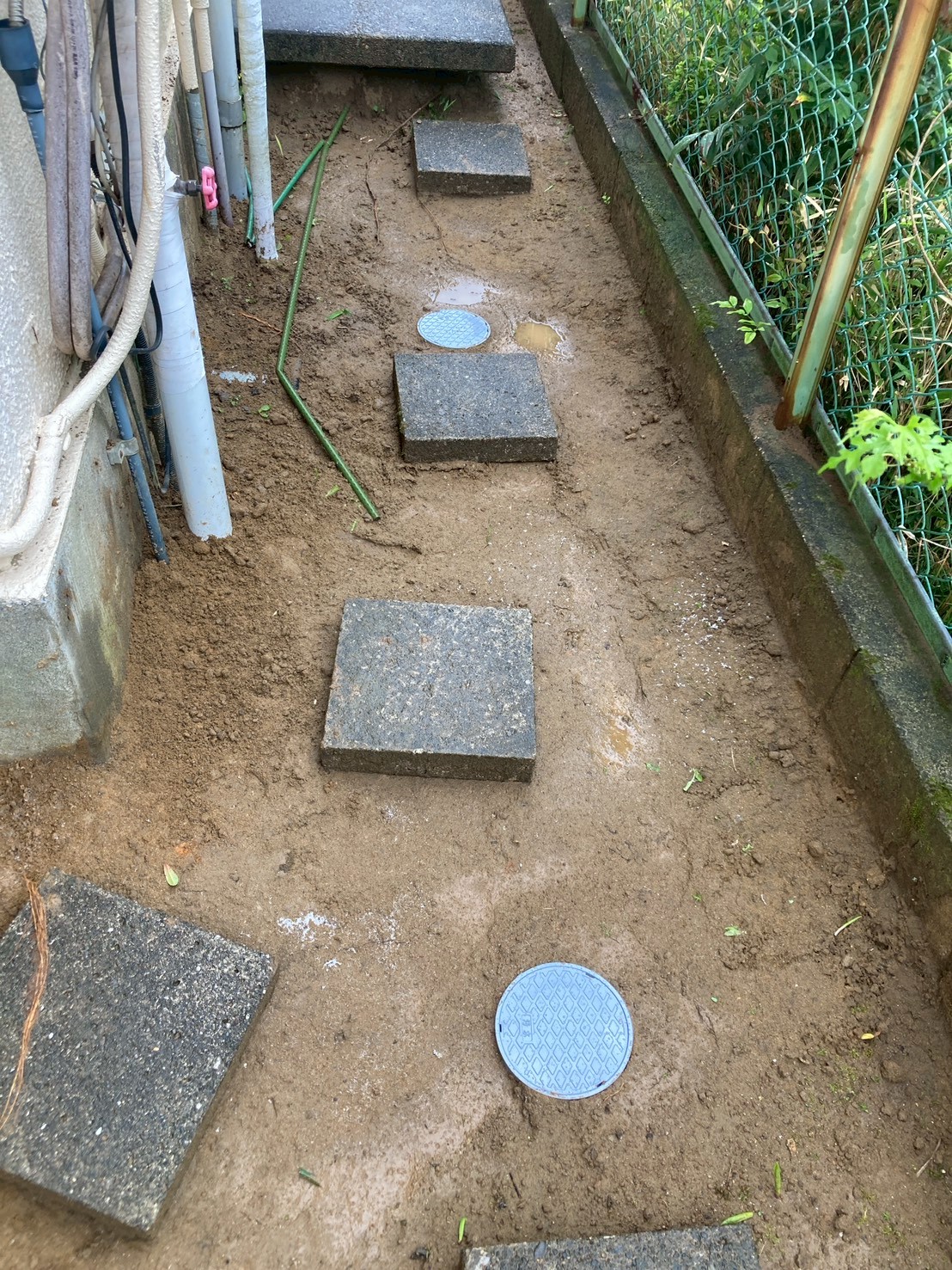 施工完了後の側面通路全景。埋め戻し・整地が完了し、新しい樹脂製会所枡の蓋が2か所地面に設置されている