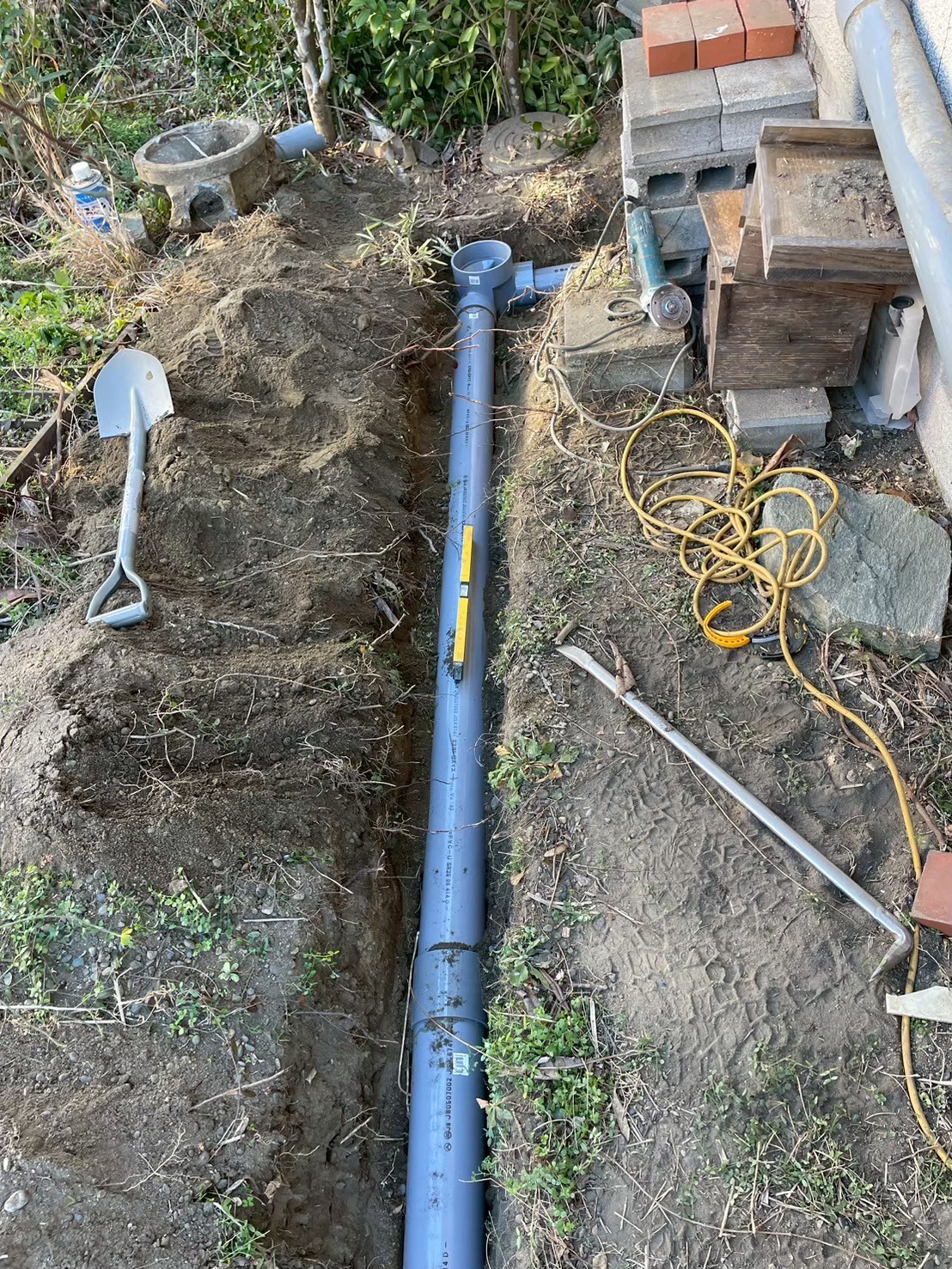 掘削溝に新規VP管全体が設置された状態。管端部に掃除口付きキャップが設けられており、将来の点検・洗浄にも対応した設計