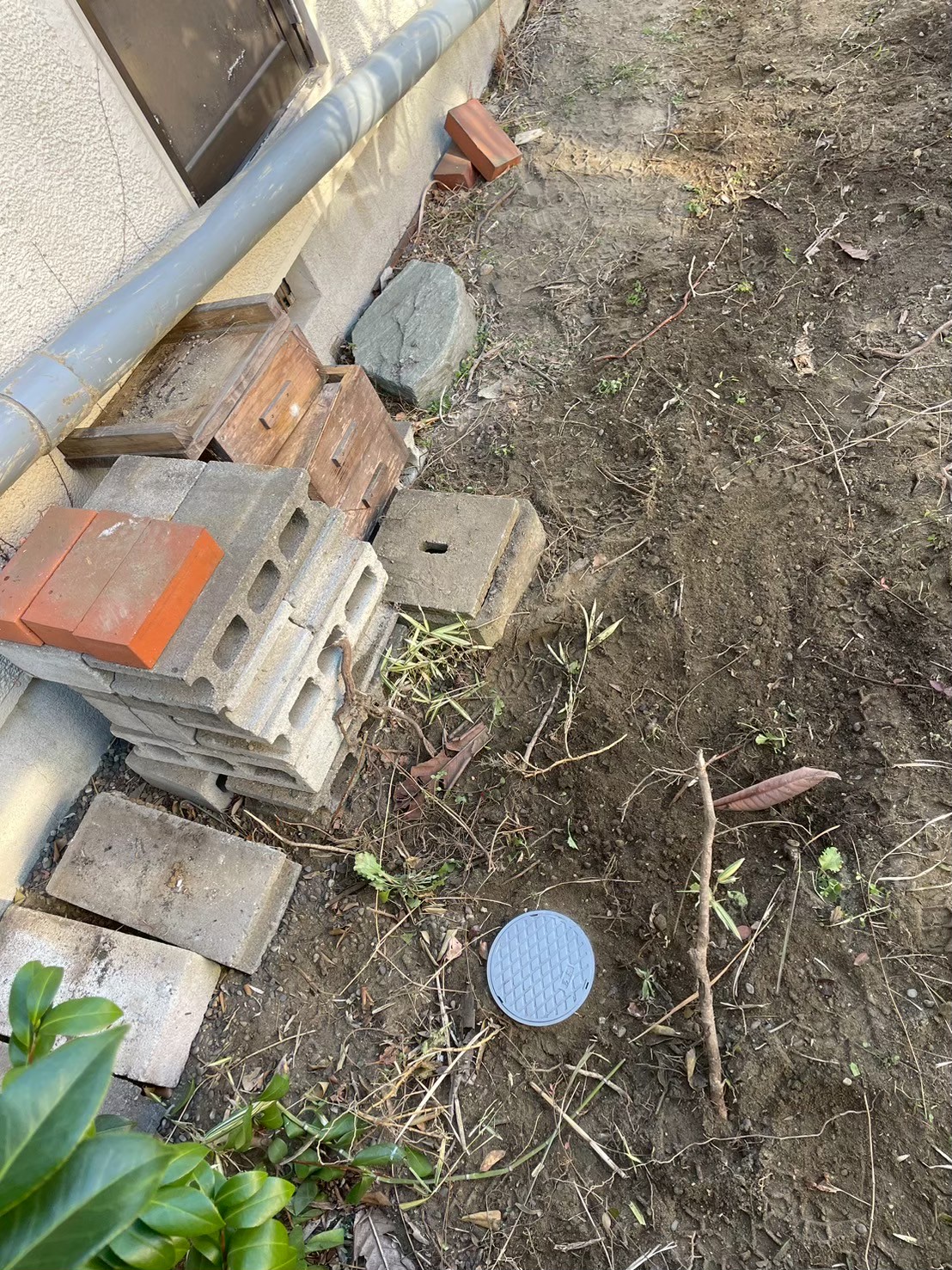 施工完了後の外構。掘削した溝が埋め戻され整地されている。新しい丸型樹脂製排水桝蓋が設置されており工事完了の状態