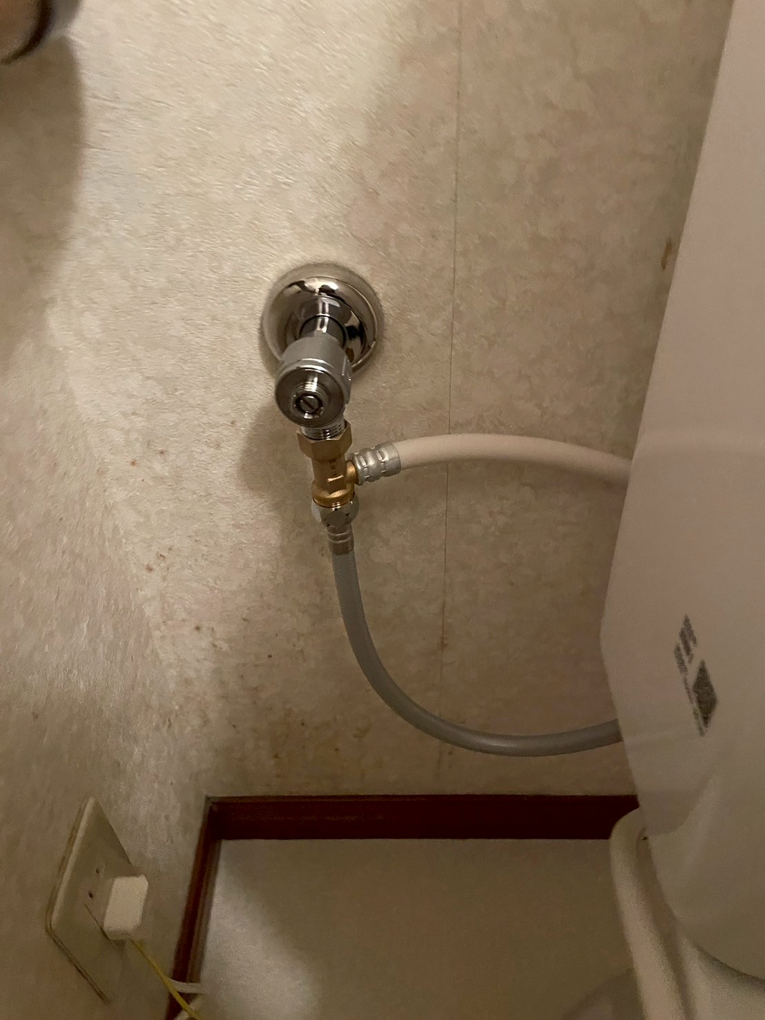 施工後の給水接続部の拡大。壁出し給水口に新品のアングル型止水栓とフレキ管が取り付けられている