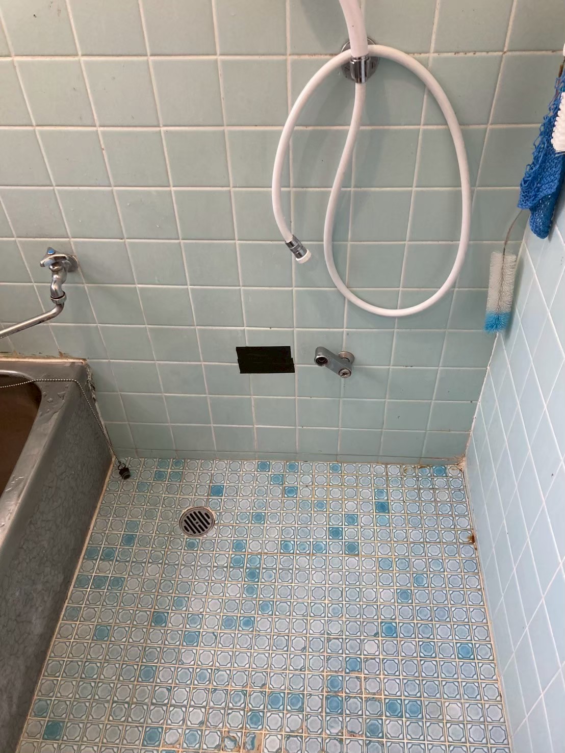 DIYで蛇口を取り外した後のタイル張り在来浴室。水栓台座だけが壁に残っている状態