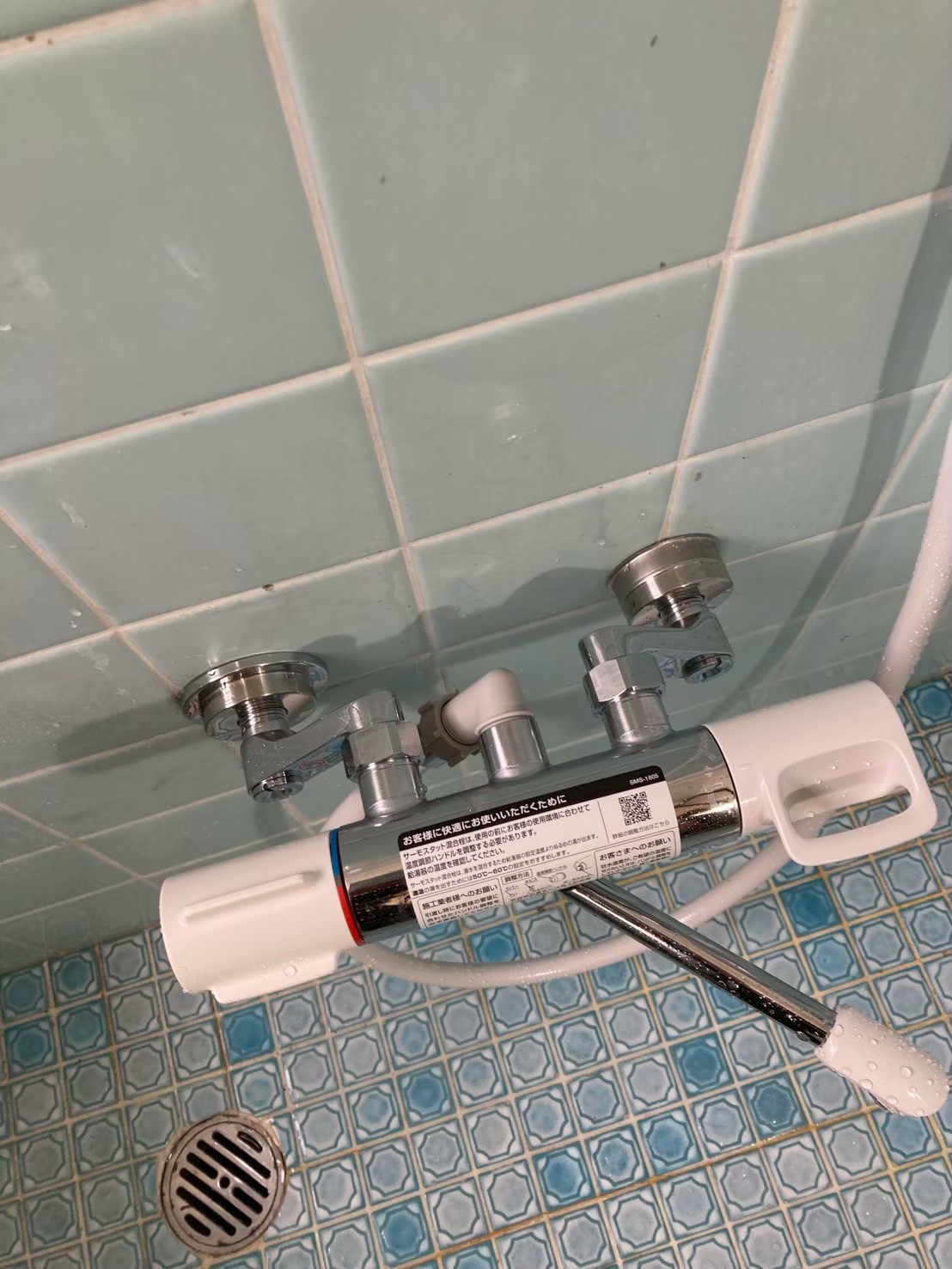 作業完了後の浴室壁。新しいサーモスタット混合水栓が取り付けられた状態