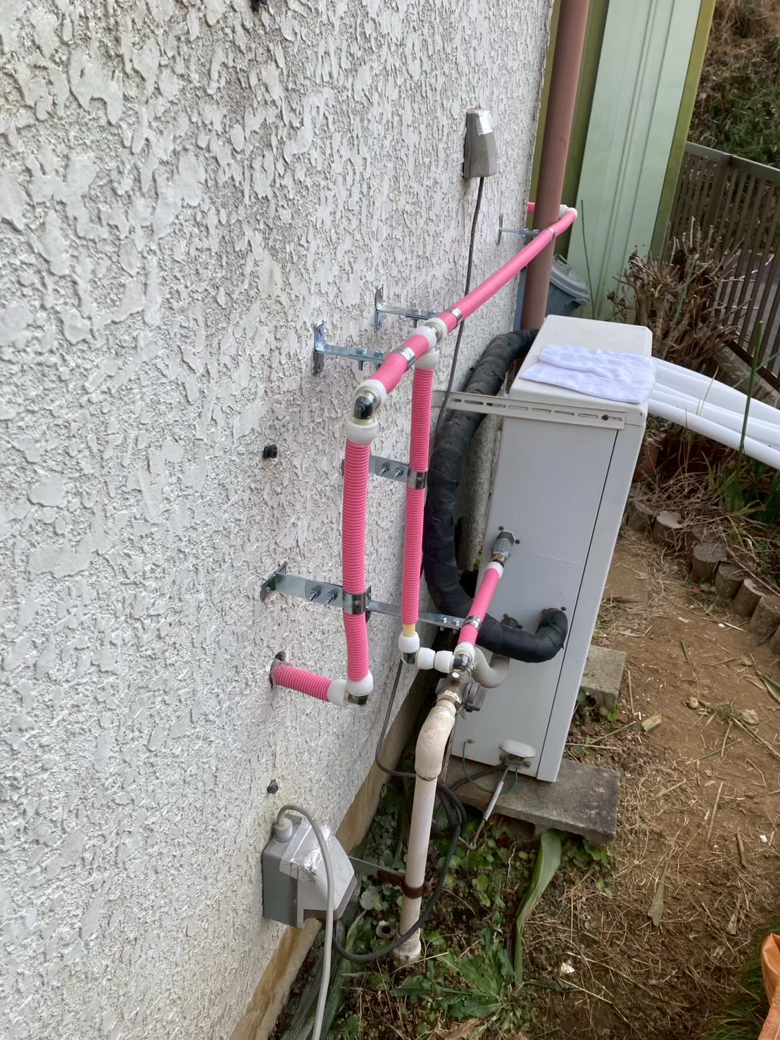 外壁面でさや管が分岐・接続されている状態。給湯器との接続部分も確認できる