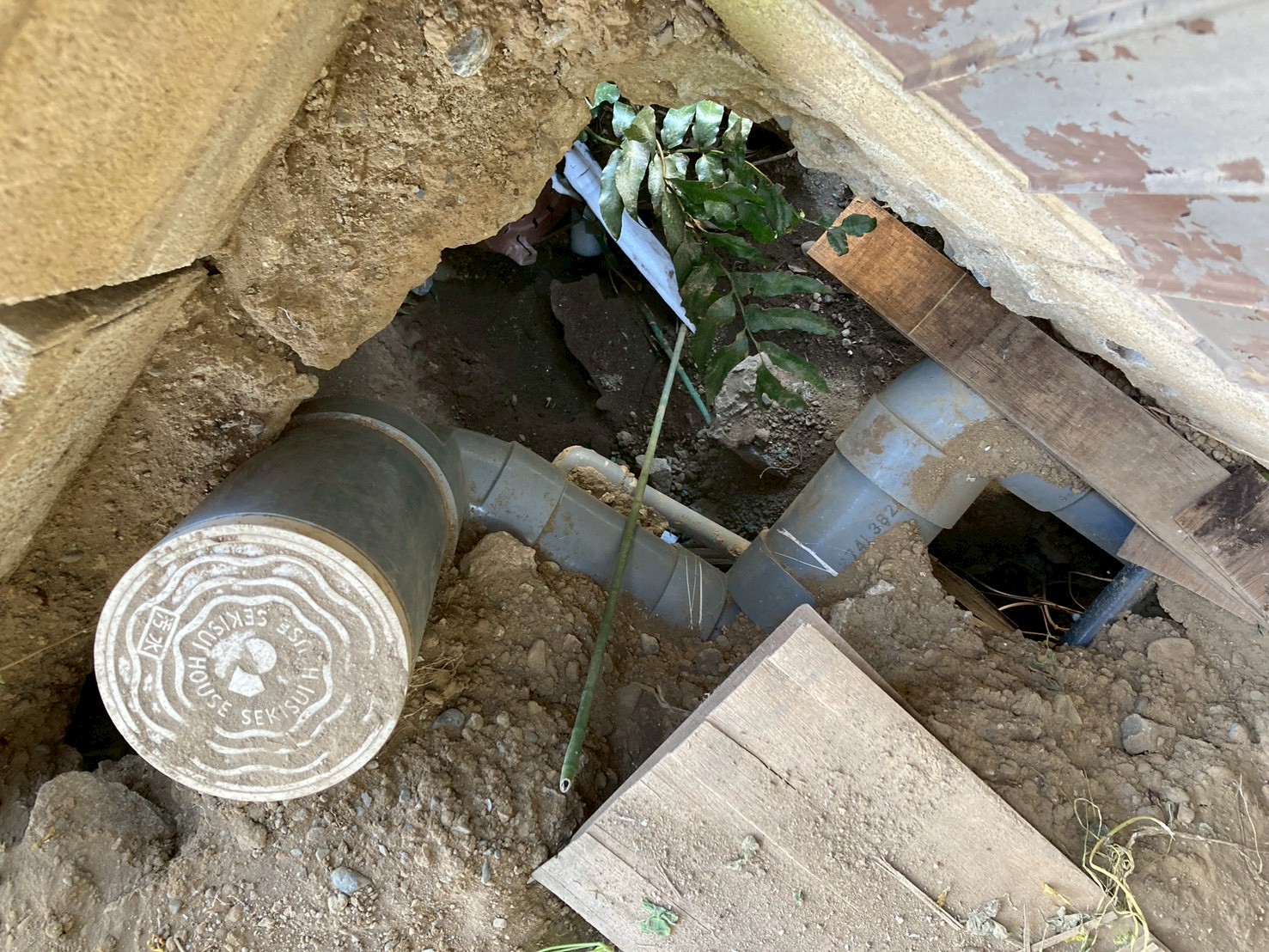 ガレージ床のコンクリートを斫り、床下の劣化した配管を掘り出した状態