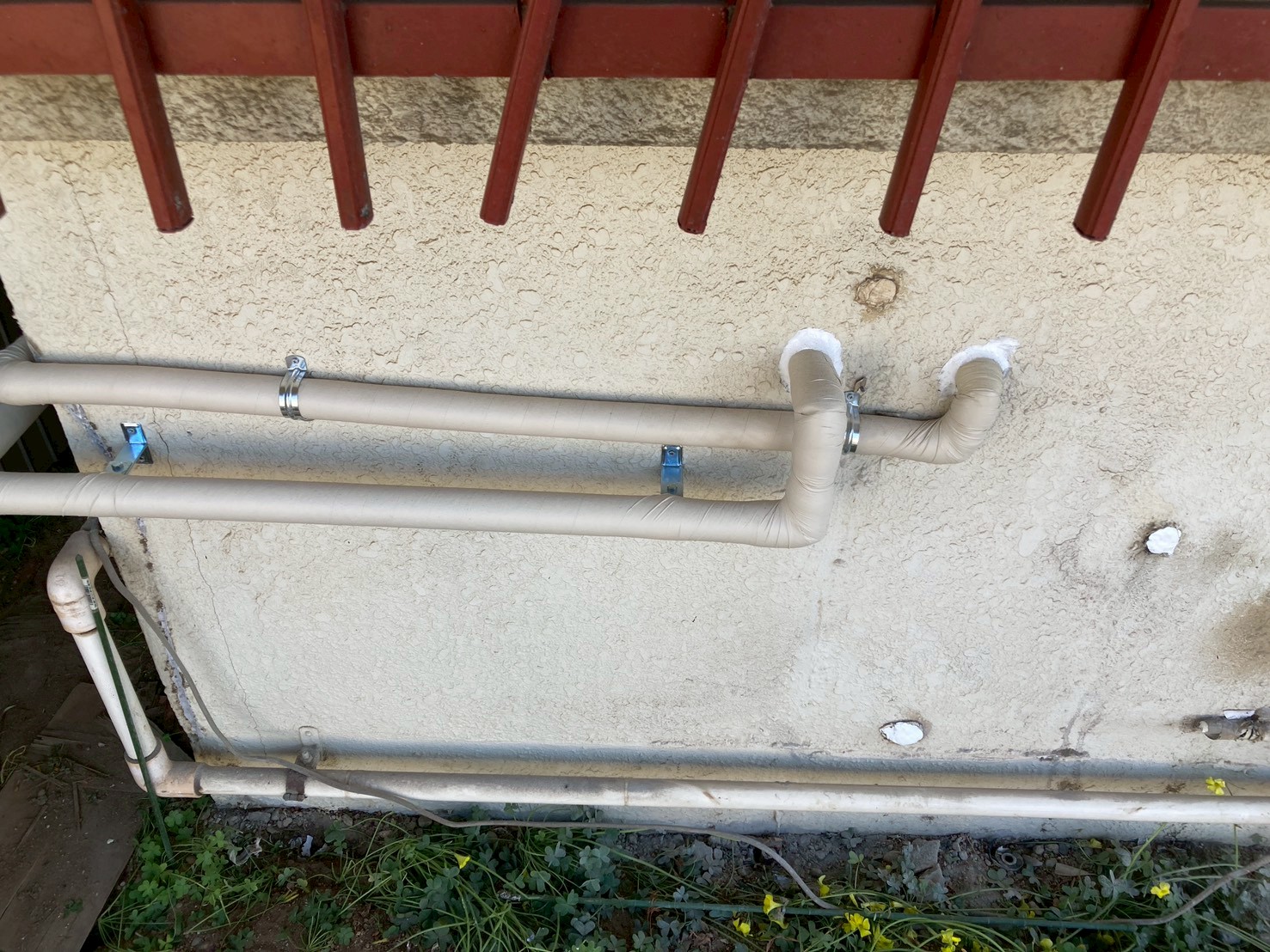 ガレージ上部の外壁に新規配管が固定金具でしっかりと取り付けられた完成後の状態