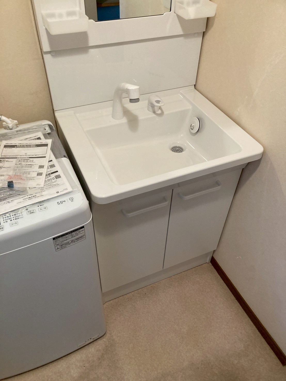 施工完了後の新しい洗面化粧台全体。白いシンプルな洗面化粧台が新品の状態で設置されている